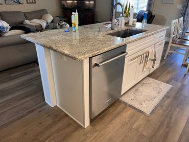 Modern kitchen island with granite countertop and stainless steel dishwasher.