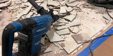 A demolition hammer on broken tile flooring during renovation work.