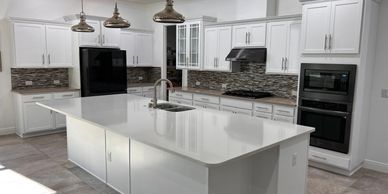 Modern kitchen with white cabinetry, large island, and pendant lights.