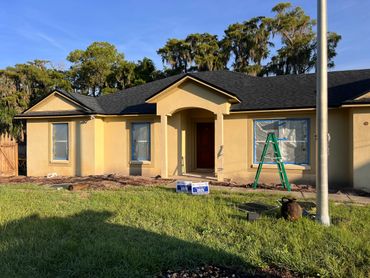 Yellow house with freshly painted walls and windows covered for protection.