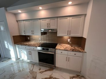 Modern kitchen with white cabinets, granite countertops, and marble flooring.