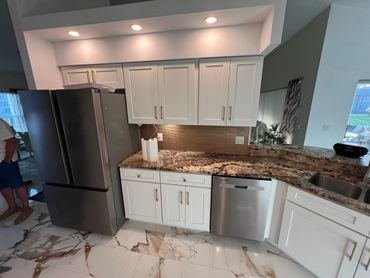 Modern kitchen with white cabinets, granite countertops, and stainless steel appliances.