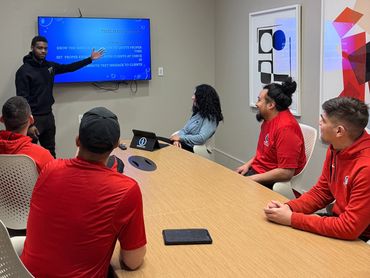 Man presenting time management tips to colleagues in a meeting room.