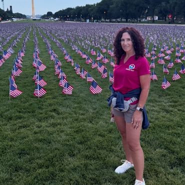 Woman standing in front of rows of American flags near the Washington Monument.