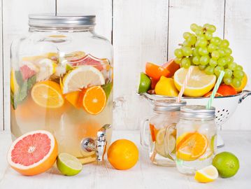 A large beverage dispenser is filled with chilled water and fresh fruits to enhance the flavor.