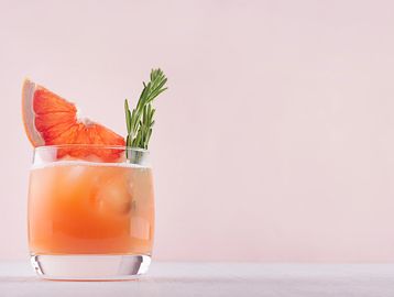 Fresh grapefruit and rosemary rest inside of a paloma cocktail.