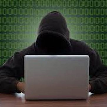 Person in hoodie using laptop with binary code background.
