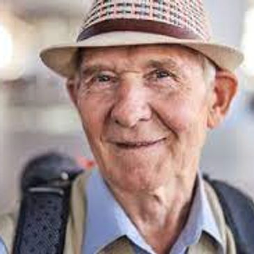 Smiling elderly man wearing a hat and backpack.