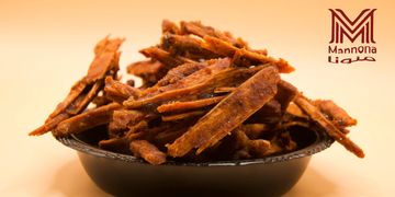 A bowl of crispy Mamona Lidia pork cracklings on a warm background.