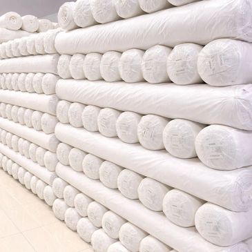 Stacks of white rolled-up mattresses or cushions neatly arranged.