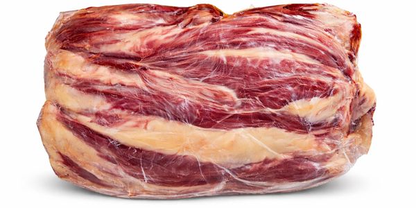 Raw beef brisket wrapped in plastic on white background.