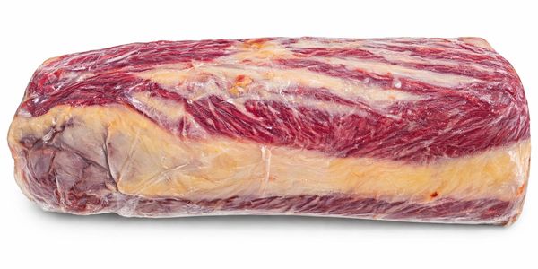 A large piece of raw beef brisket wrapped in plastic.