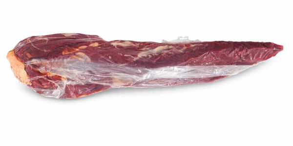 A vacuum-sealed raw beef tenderloin on a white background.