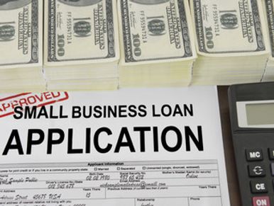 Image of a small business loan application with stacks of money and a calculator.