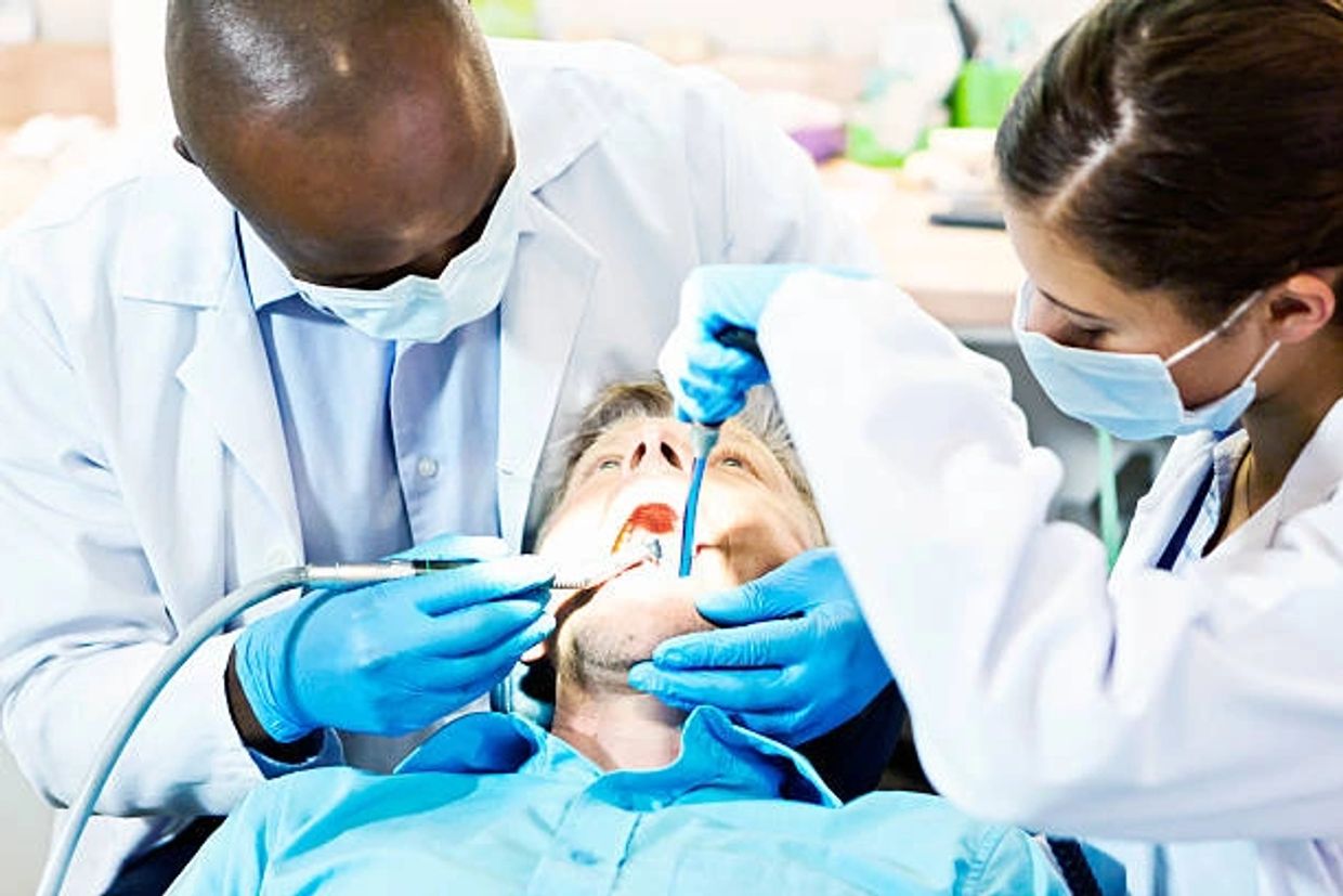 Dentists and his assistant performing a procedure on a patient.