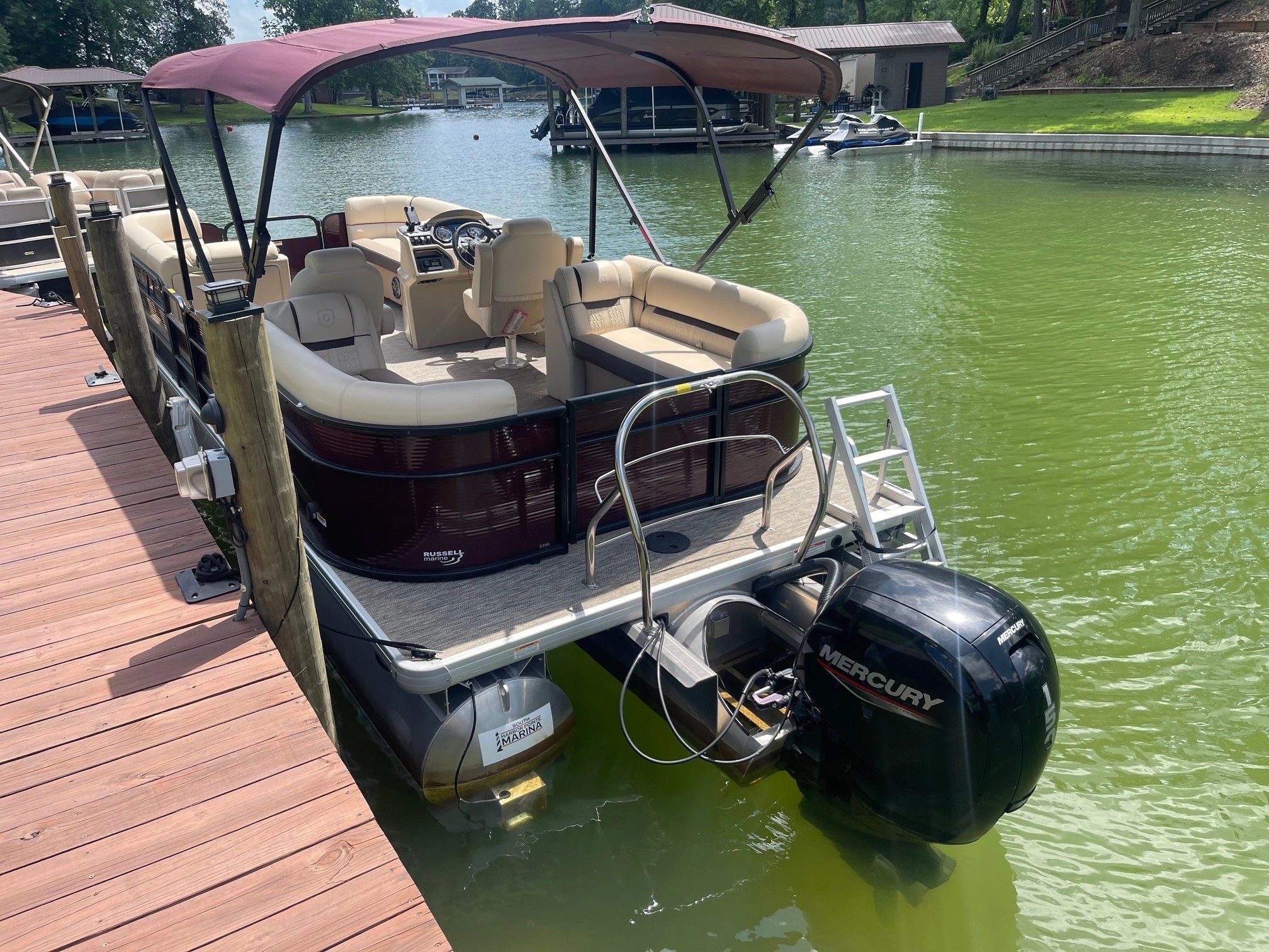 Pontoon boat docked in a marina with green water.