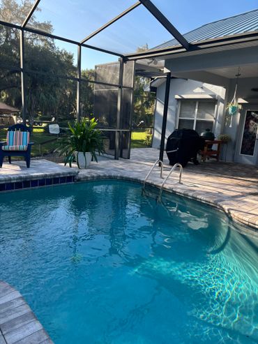 A backyard swimming pool with clear blue water and surrounding patio area.