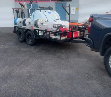 A utility trailer with tanks, hoses, and equipment hitched to a truck.