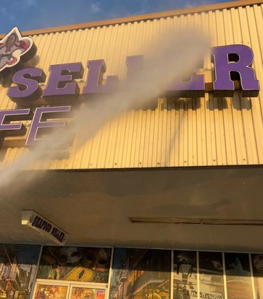 Water spraying on Seafood Seller sign on a yellow building.