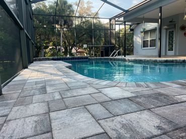 A serene backyard pool with a screened enclosure and stone tile deck.