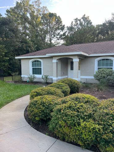 Suburban house with curved sidewalk and neatly trimmed bushes.