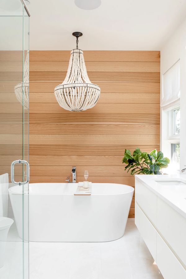 interior design renovated modern bathroom with custom wood feature wall  beaded chandelier over tub