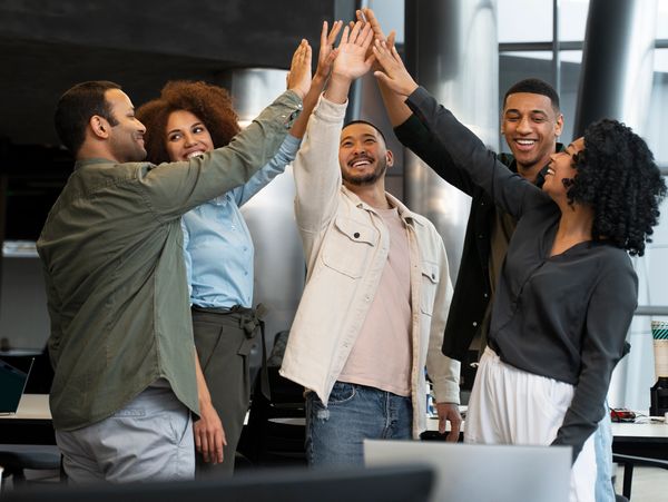 A group of colleagues giving a high-five in a modern office setting.