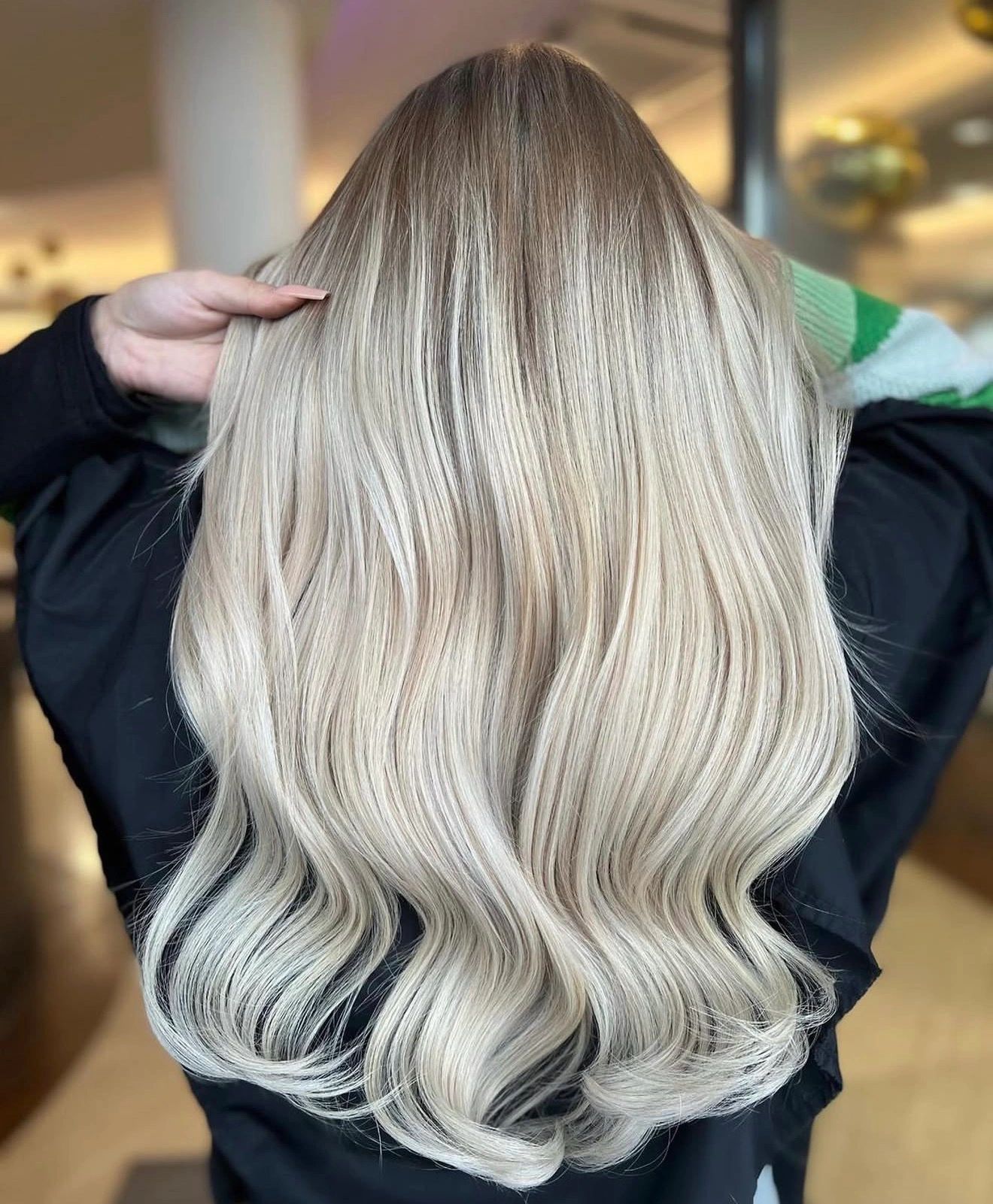 Lange, wellige aschblonde Haare mit dunklen Wurzeln.