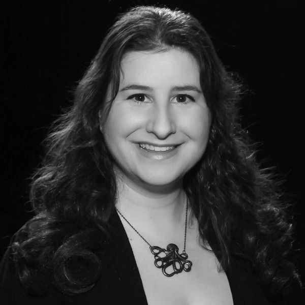 A black and white photo of Lisa. She is smiling, wearing a necklace of an octopus. 