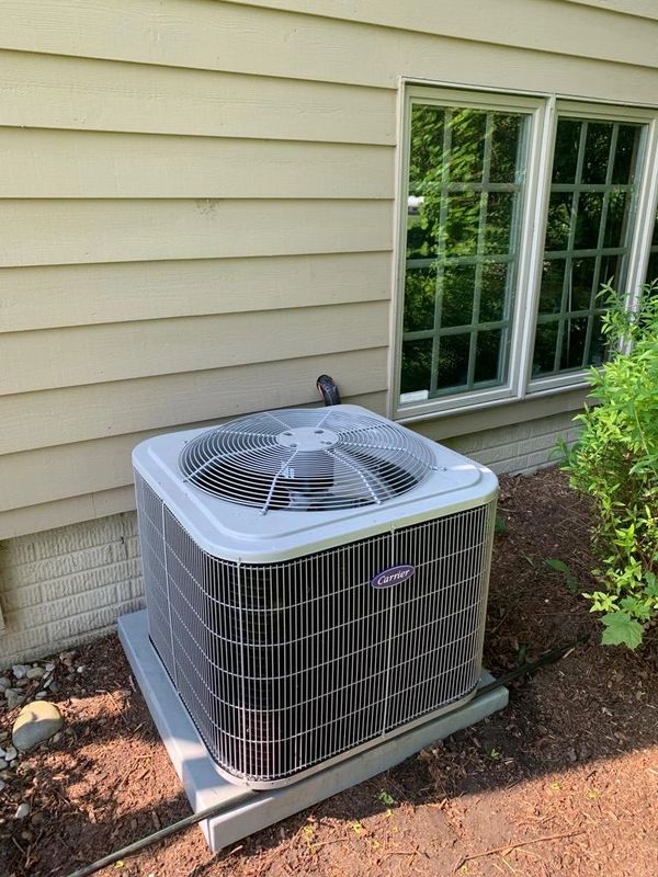 Outdoor Carrier air conditioning unit installed beside a house.
