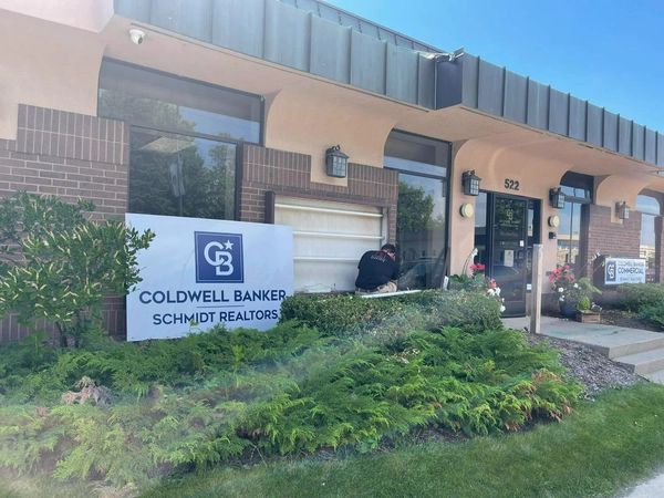 Coldwell Banker Schmidt Realtors office with a man working outside.