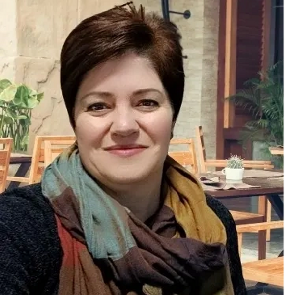 A woman smiling at an outdoor cafe with a colorful scarf.