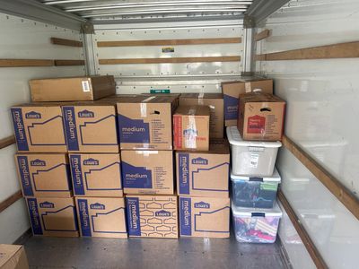 Stacked moving boxes and storage containers inside a truck.