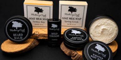A collection of goat milk soap and grooming products on a black background.