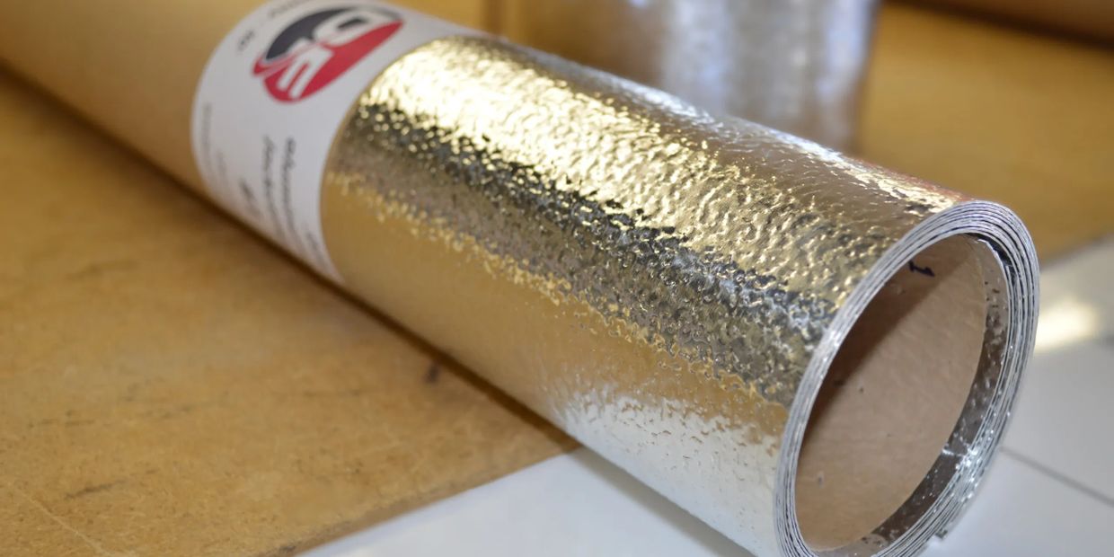 A roll of reflective silver insulating material on a wooden surface.