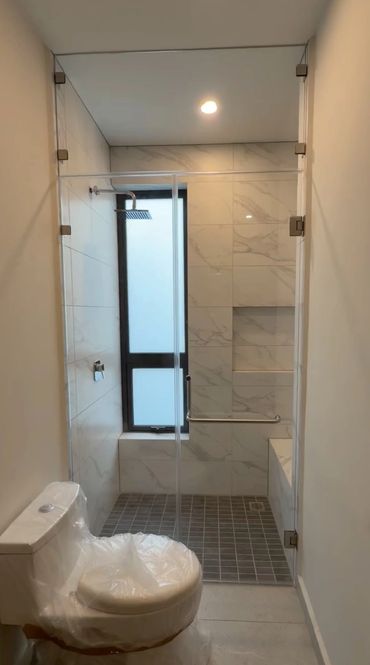 Modern bathroom with glass shower enclosure and marble tiles.
