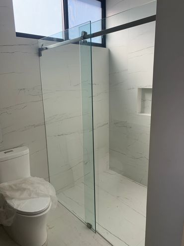 Modern bathroom with glass shower enclosure and white marble tiles.