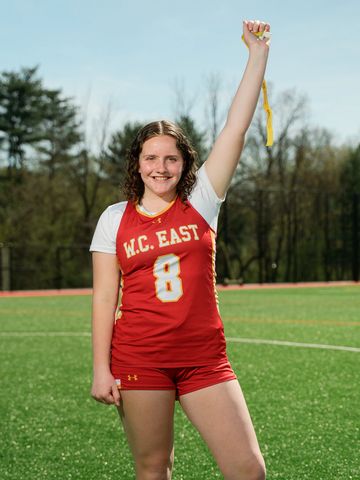 Young athlete in red uniform celebrating on a sports field.