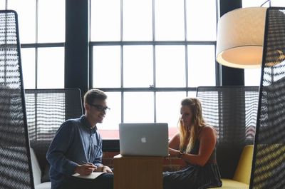 Two people collaborating on a laptop in a modern office space.