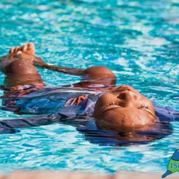 A child floating peacefully on their back in a swimming pool.