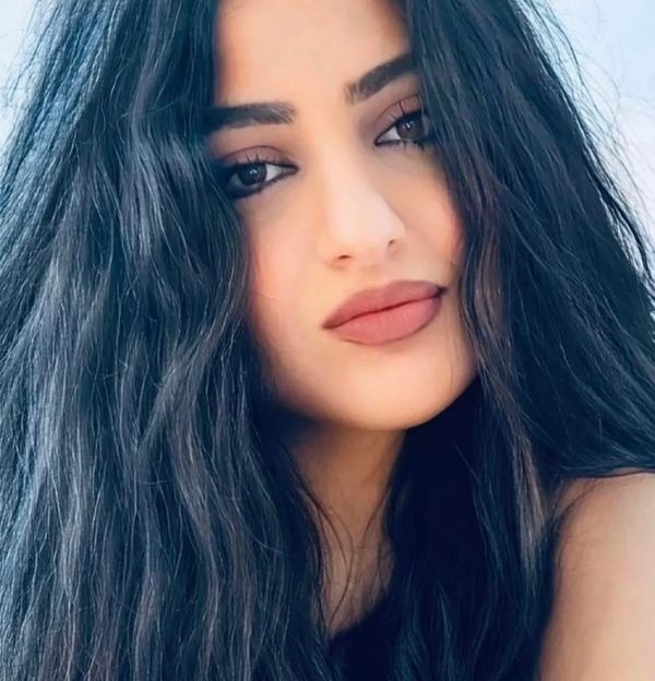Close-up portrait of a woman with long black hair and natural makeup.