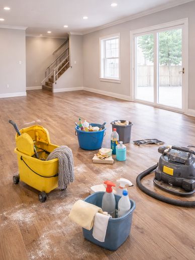 Cleaning supplies and equipment in an empty room with wooden floors.