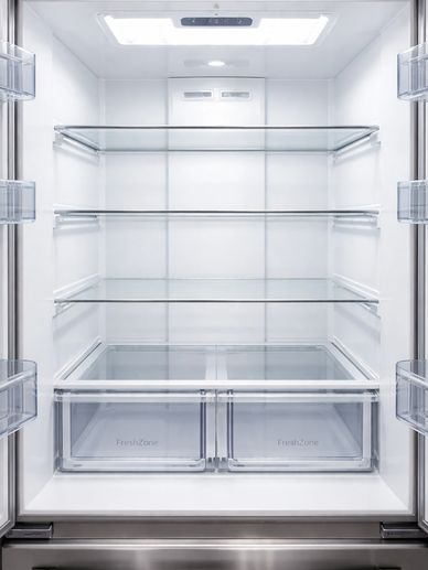 Empty refrigerator interior with glass shelves and fresh zone drawers.