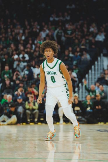 Basketball player in white uniform reacting on court.