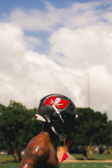 Football player wearing a Tampa Bay Buccaneers helmet on a field.