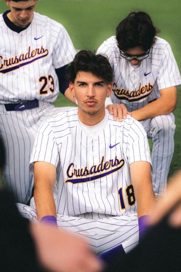 Baseball players in striped Crusaders uniforms posing on the field.