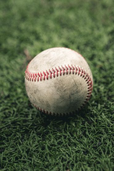 Close-up of a worn baseball on grass.