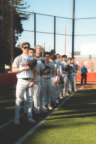 Baseball team lined up holding their hats.