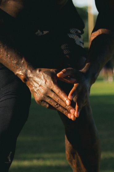 Athlete holding injured knee outdoors.