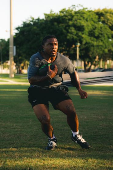 Athlete running with resistance band on field.